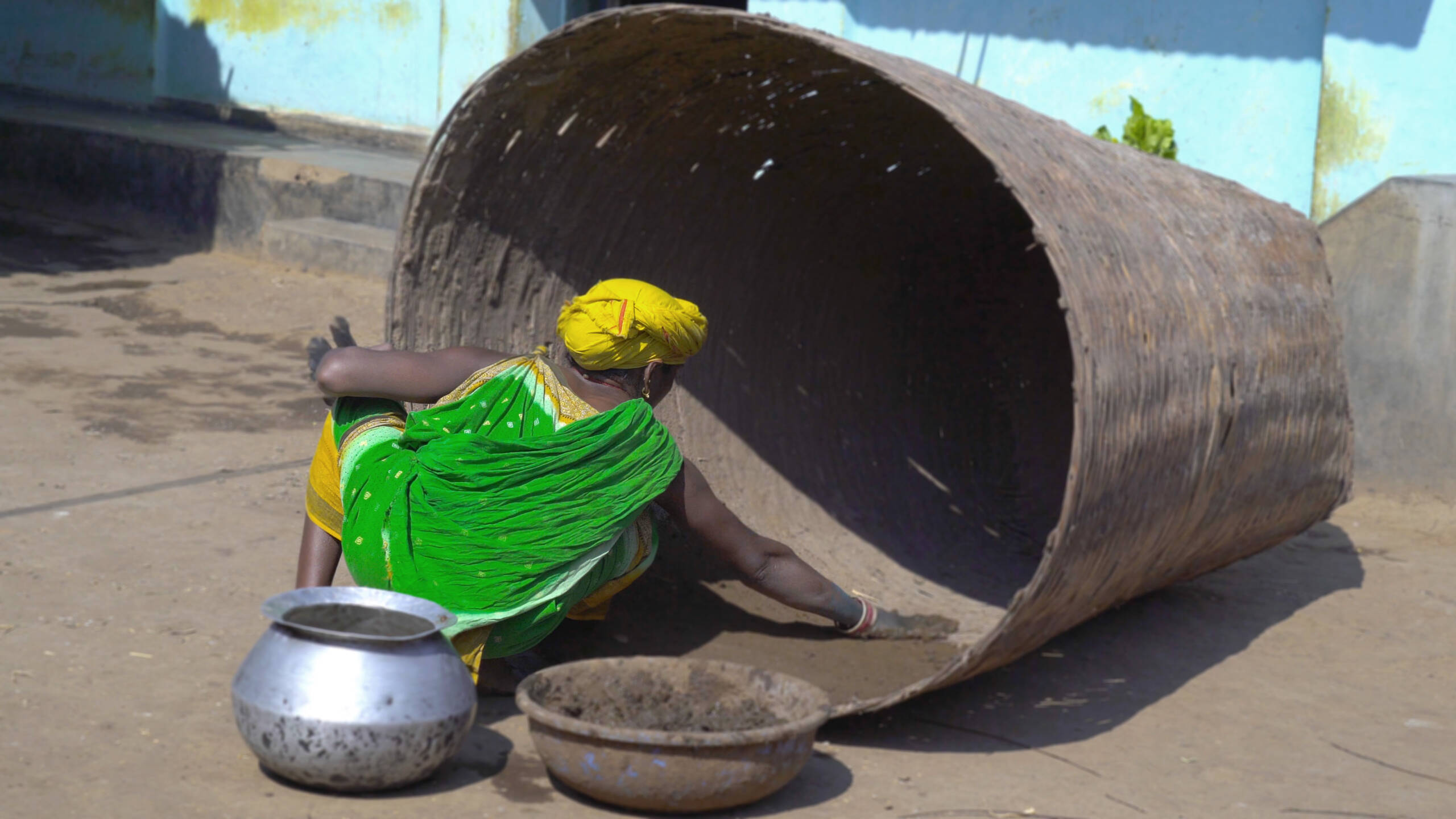 Paroja woman plastering the grain bin